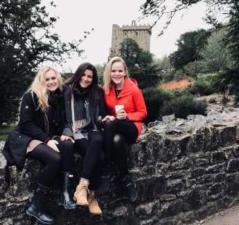 3 Creighton student sitting on stone wall