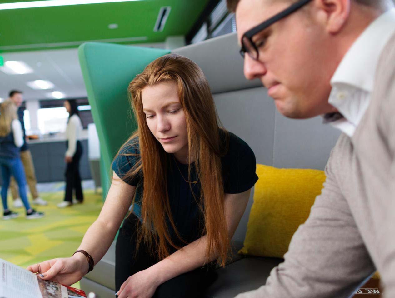 Two people looking over brochure in business setting.