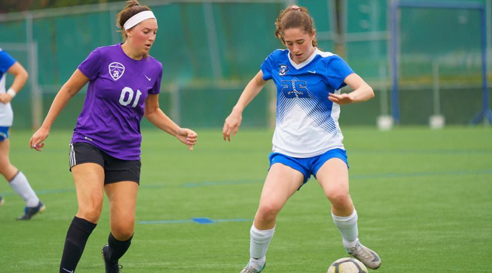 Two women club soccer players competing.