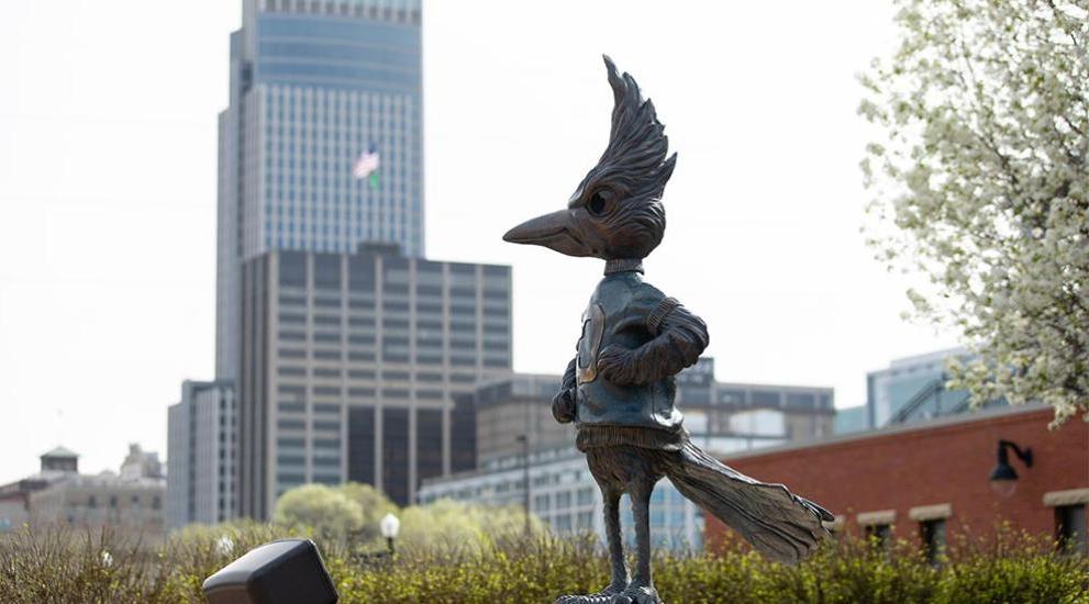 Billy Bluejay statue in front of Omaha skyline